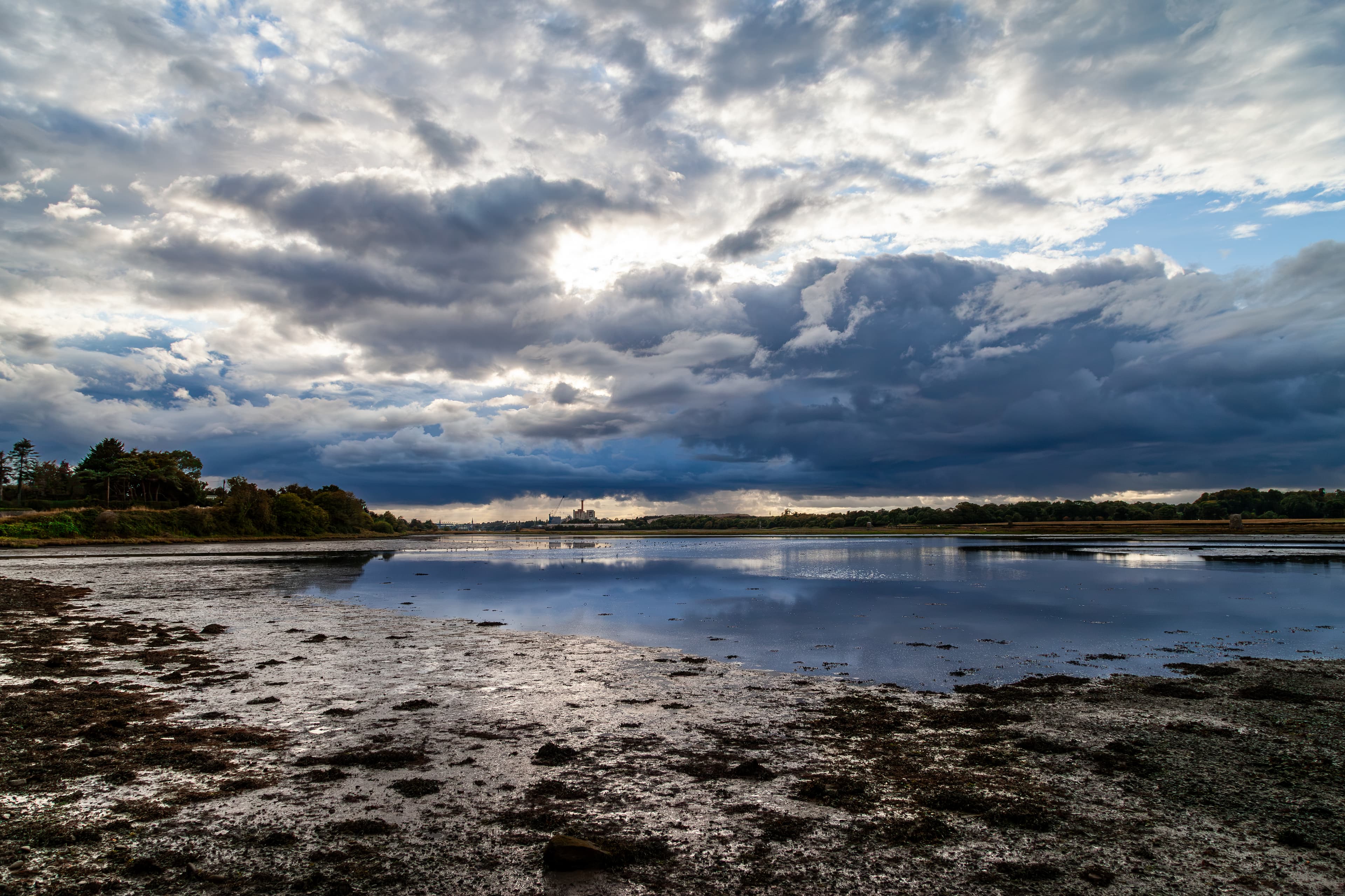 Moody coastal light over still water at low tide